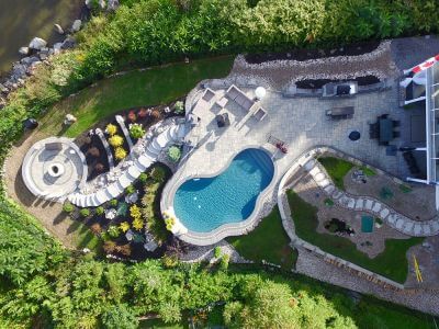 aerial view of beautifully landscaped back yard with stone work and inground pool