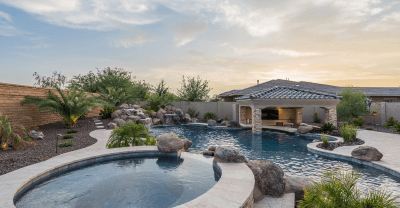 Landscape of a home with pool and spa with decorative boulders